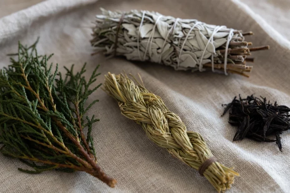 Four sacred herbs such as cedar, sage, sweetgrass and loose tobacco on a textured beige fabric