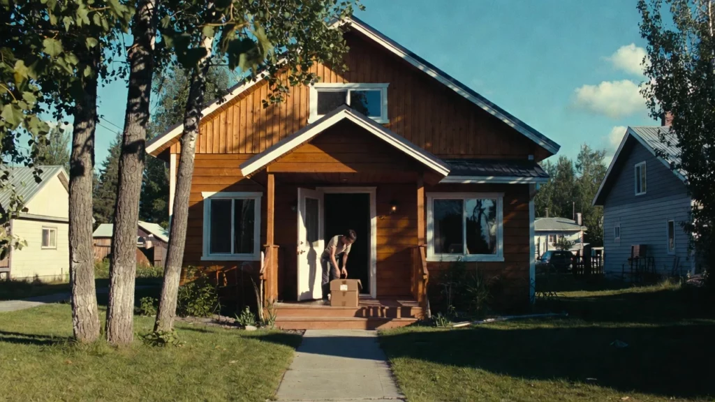 A man grabbing his kratom package delivery at the front door of a wooden cabin-style home